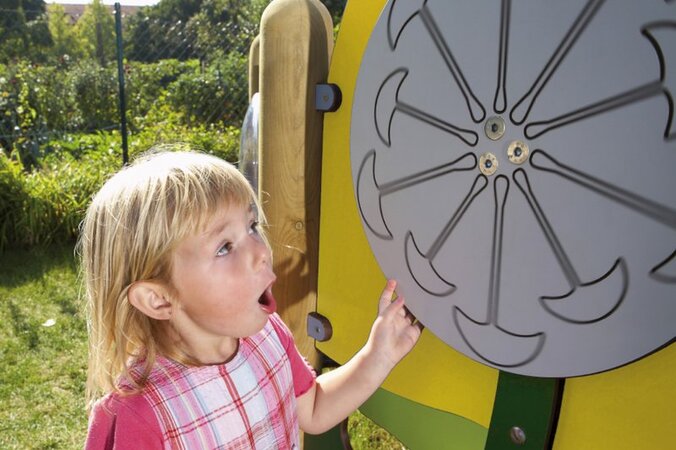 une petite fille tourne une roue de aire de jeux jaune de eibe