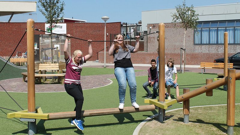 Un groupe de jeunes en équilibre sur des jeux eibe dans la cour de récréation